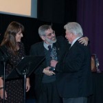 Luis Puenzo recebendo o trofeú Lente de Cristal da Ministra Conselheira da Embaixada do Brasil Gisela Padovan e Marcio Cameron do BNDES